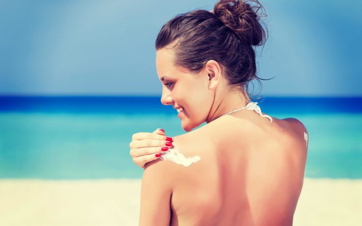Woman applying nontoxic sunscreen to shoulder
